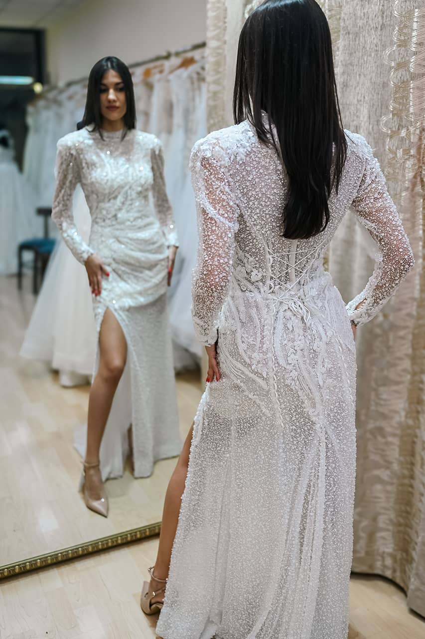 Venčanica sa dugim rukavima, šljokicama i šlicem tokom probe ispred ogledala